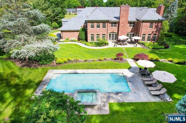 back of house with a swimming pool with hot tub, a yard, and a patio area