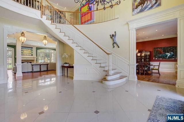 stairway with decorative columns, crown molding, and a towering ceiling