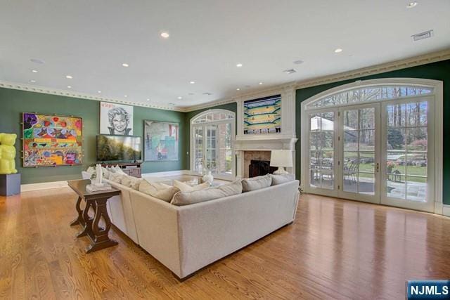 living room featuring crown molding, light wood-type flooring, and french doors