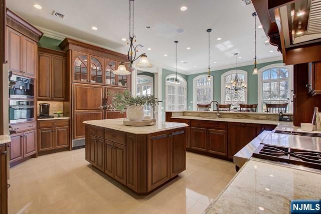 kitchen with pendant lighting, double oven, crown molding, and a spacious island