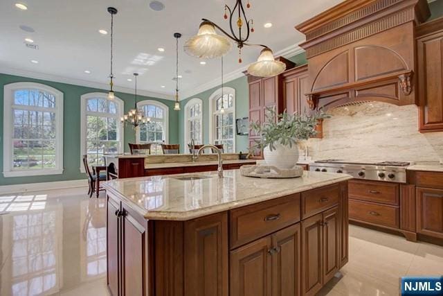 kitchen with decorative light fixtures, an island with sink, sink, stainless steel gas cooktop, and custom range hood