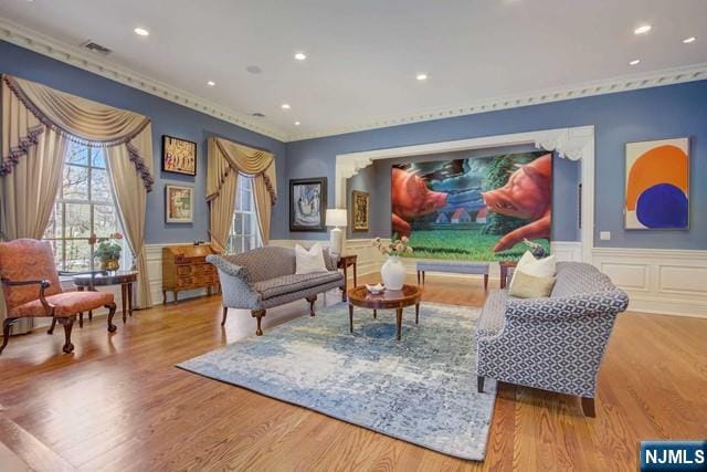 sitting room with ornamental molding and light wood-type flooring