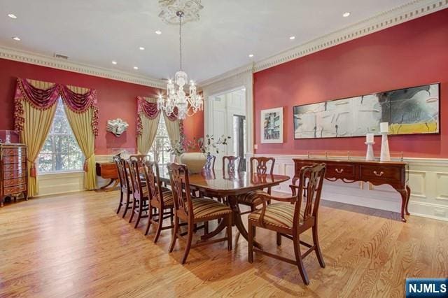 dining space with ornamental molding, a chandelier, and light hardwood / wood-style floors