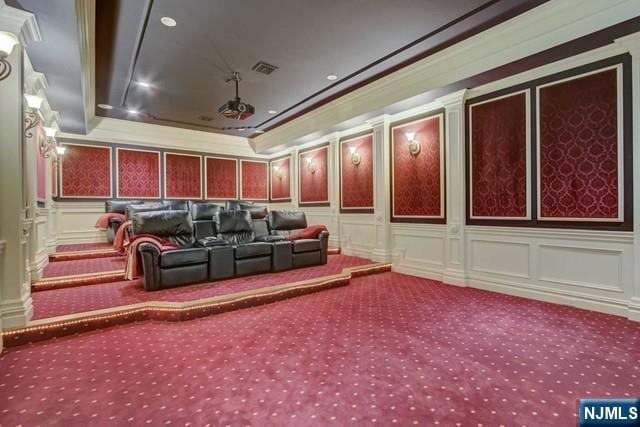 home theater with a tray ceiling, crown molding, and carpet