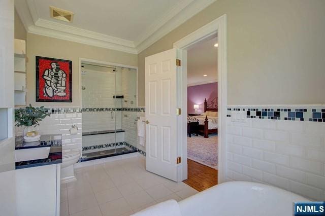 bathroom featuring tile patterned floors, ornamental molding, a bath, and tile walls