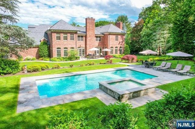 view of swimming pool with an in ground hot tub, a yard, and a patio area