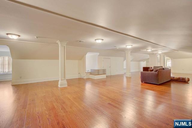 unfurnished living room featuring decorative columns and light wood-type flooring