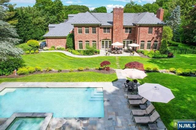 back of house with a swimming pool with hot tub, a lawn, and a patio