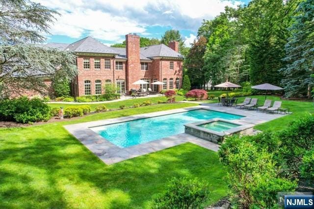 view of swimming pool with a yard, a patio area, and an in ground hot tub