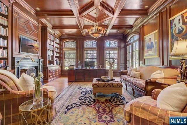 sitting room with built in features, hardwood / wood-style flooring, coffered ceiling, crown molding, and beam ceiling