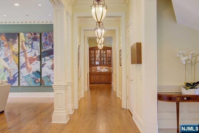 corridor with ornate columns and light wood-type flooring