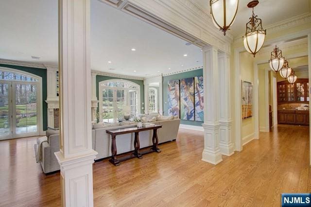 corridor featuring crown molding, light hardwood / wood-style floors, french doors, and ornate columns