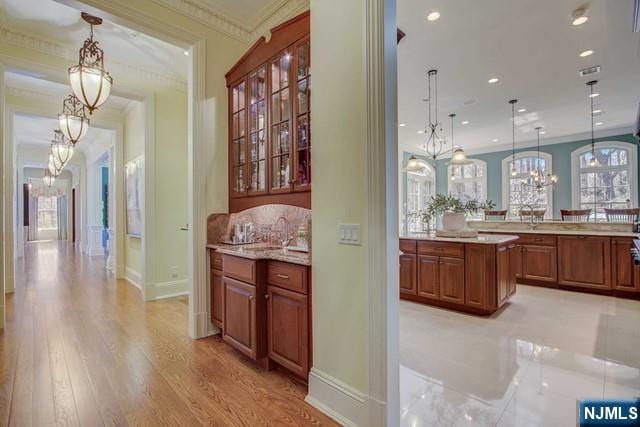 interior space with sink, crown molding, a chandelier, hanging light fixtures, and light hardwood / wood-style floors