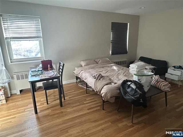 bedroom featuring radiator, light wood-style floors, and baseboards