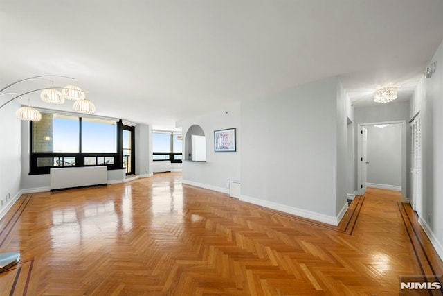 spare room featuring light parquet flooring and a chandelier