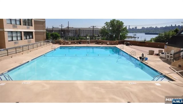 view of pool with a water view and a patio