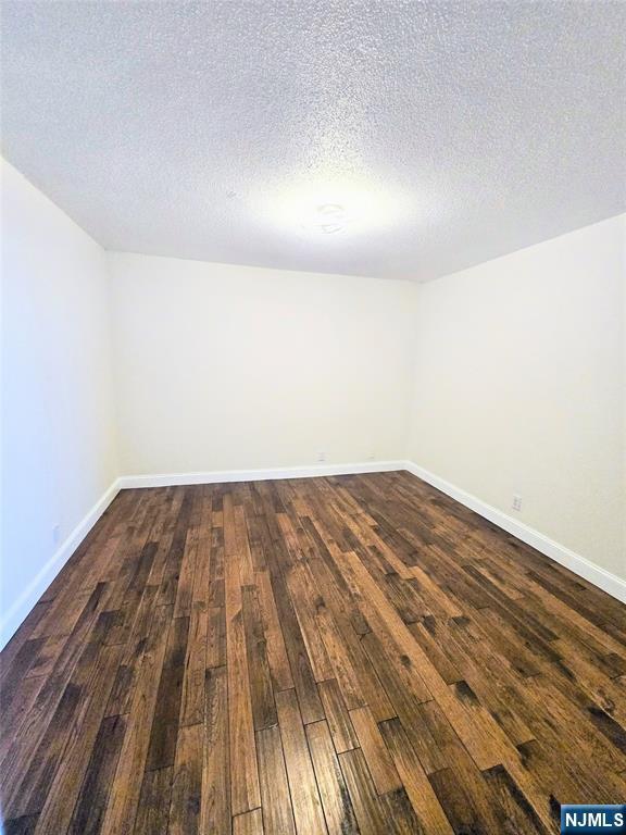 unfurnished room with dark hardwood / wood-style floors and a textured ceiling