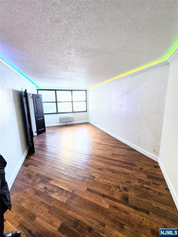 unfurnished living room with dark wood-type flooring and a textured ceiling