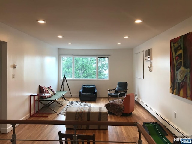 living area featuring a baseboard heating unit and hardwood / wood-style floors