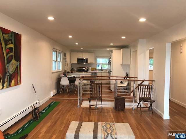 kitchen featuring appliances with stainless steel finishes, hardwood / wood-style floors, a baseboard radiator, sink, and white cabinets