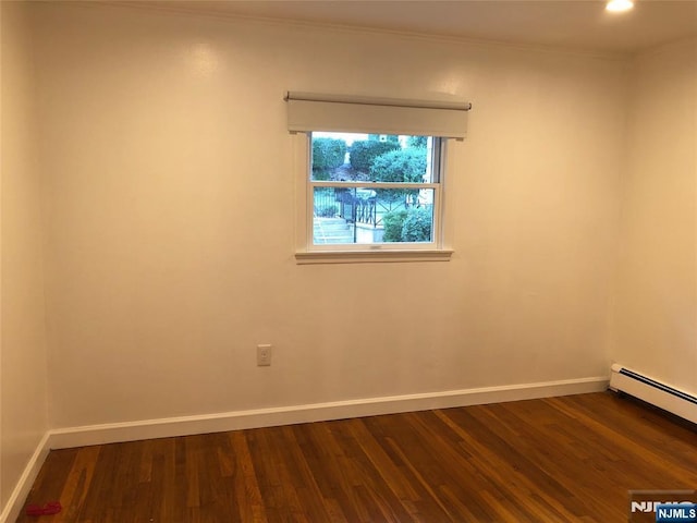 unfurnished room with crown molding, dark hardwood / wood-style flooring, and a baseboard heating unit