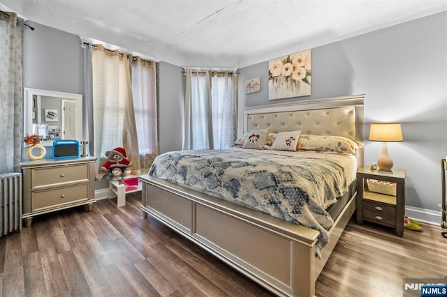 bedroom with dark wood-type flooring and radiator heating unit