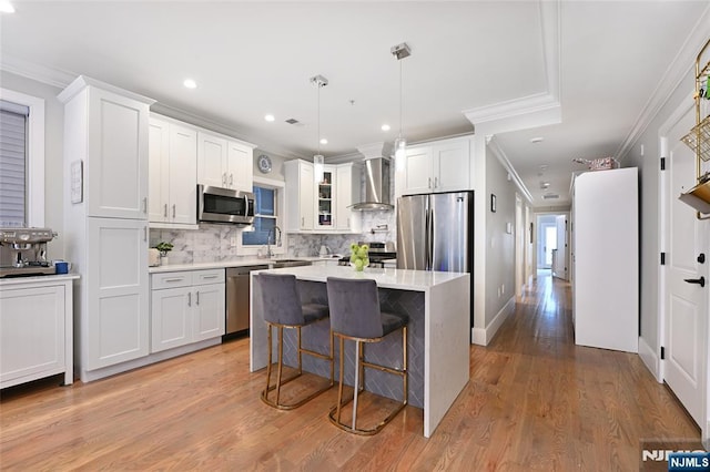 kitchen featuring sink, wall chimney exhaust hood, white cabinets, and appliances with stainless steel finishes