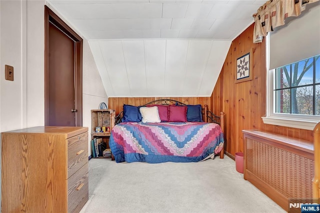 carpeted bedroom with lofted ceiling, radiator, and wooden walls