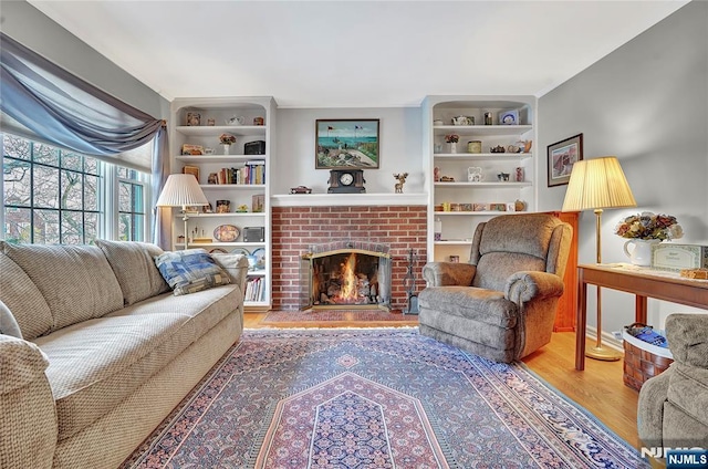 living room featuring wood-type flooring, a fireplace, and built in shelves