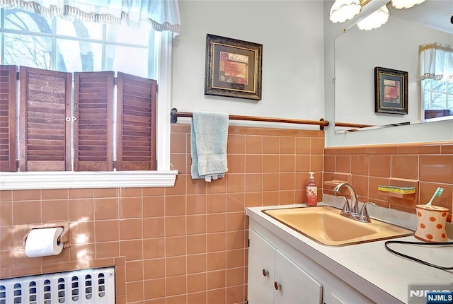 bathroom featuring vanity, radiator heating unit, and tile walls