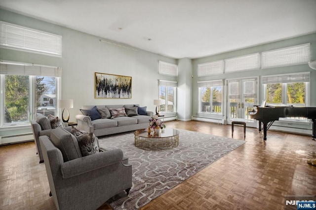 living room with a baseboard heating unit, a towering ceiling, parquet flooring, and plenty of natural light