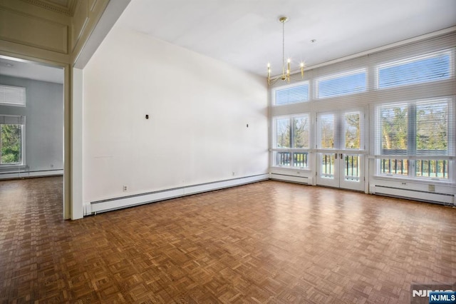 empty room with parquet flooring, a healthy amount of sunlight, an inviting chandelier, and baseboard heating