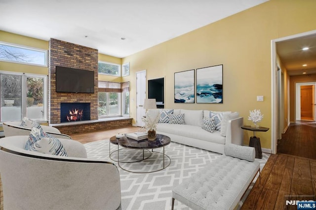 living room featuring wood-type flooring and a brick fireplace