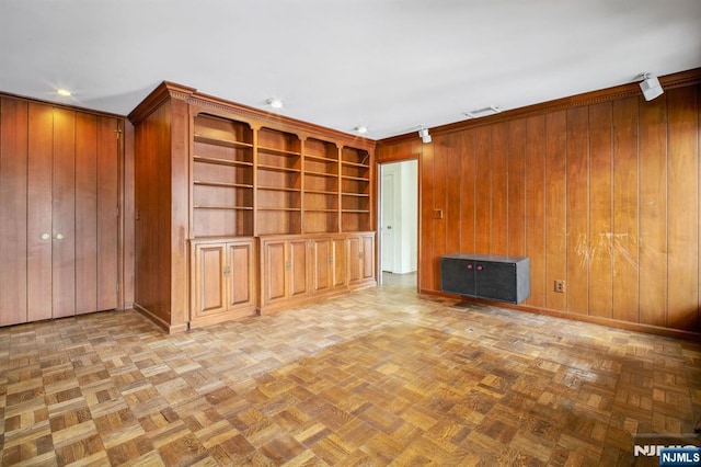 unfurnished living room featuring parquet floors, crown molding, and wood walls