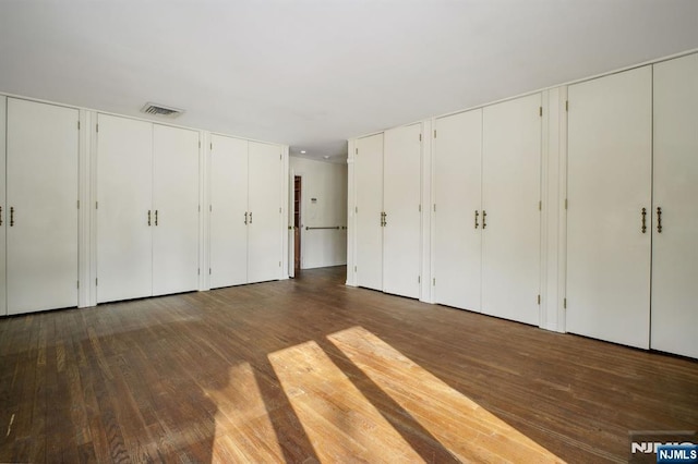 unfurnished bedroom with dark wood-type flooring and two closets