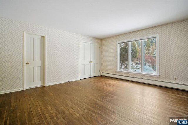 unfurnished bedroom featuring wood-type flooring and baseboard heating