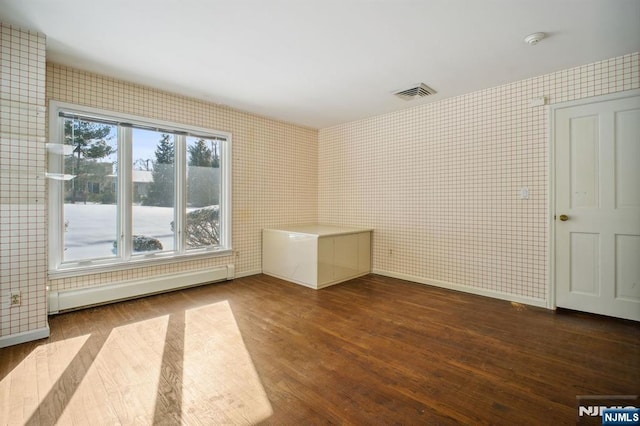 empty room with hardwood / wood-style floors and baseboard heating