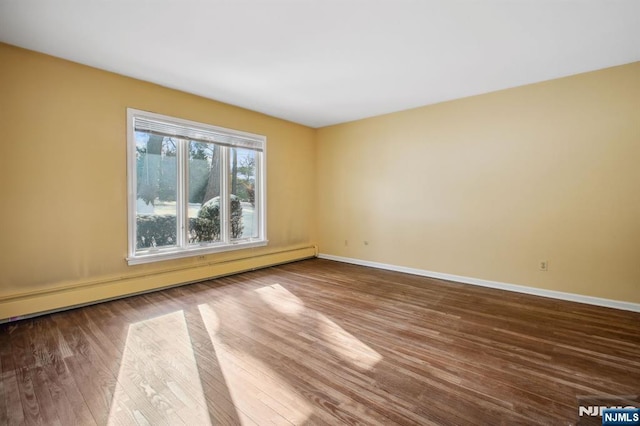 spare room featuring hardwood / wood-style flooring and a baseboard heating unit