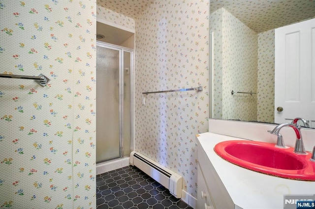 bathroom with a baseboard radiator, vanity, and a shower with door