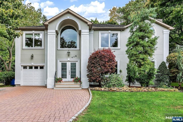 view of front facade with a garage, french doors, and a front lawn