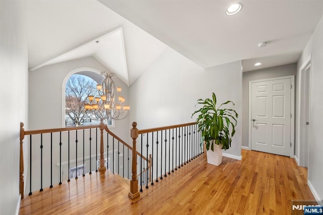 hallway with vaulted ceiling, a notable chandelier, and light hardwood / wood-style flooring