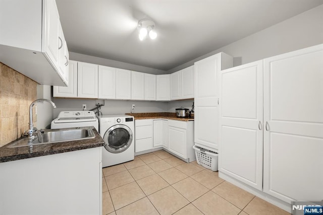 clothes washing area featuring cabinets, washer and clothes dryer, sink, and light tile patterned floors