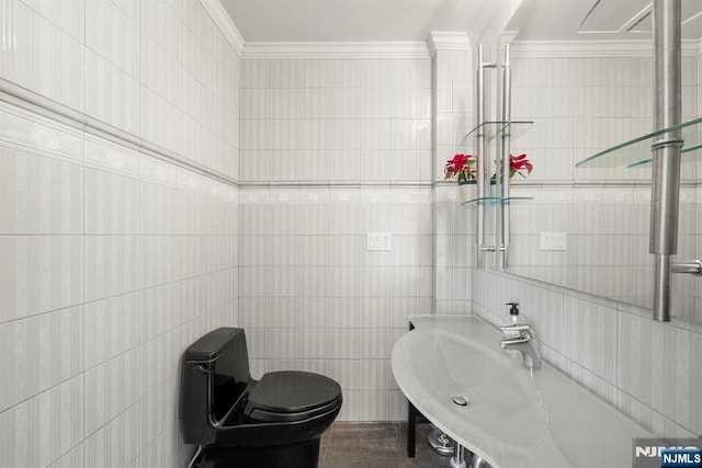 bathroom with crown molding, toilet, sink, and tile walls