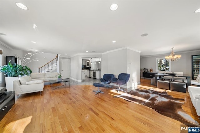 living room featuring ornamental molding, a notable chandelier, and light hardwood / wood-style floors