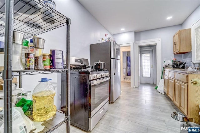 kitchen with appliances with stainless steel finishes, sink, and light brown cabinets