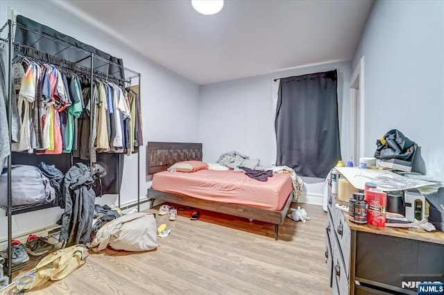 bedroom with a baseboard heating unit and light hardwood / wood-style flooring