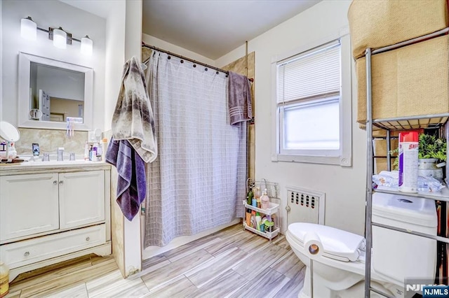 bathroom featuring a shower with curtain, radiator heating unit, toilet, and vanity