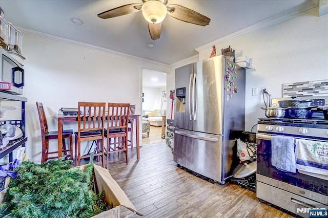 kitchen with crown molding, appliances with stainless steel finishes, ceiling fan, and light hardwood / wood-style floors