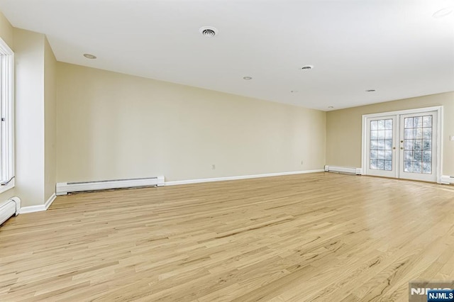 spare room featuring baseboard heating, french doors, and light wood-type flooring