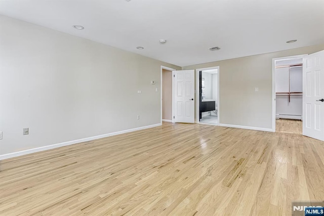 unfurnished room with a baseboard heating unit and light hardwood / wood-style floors